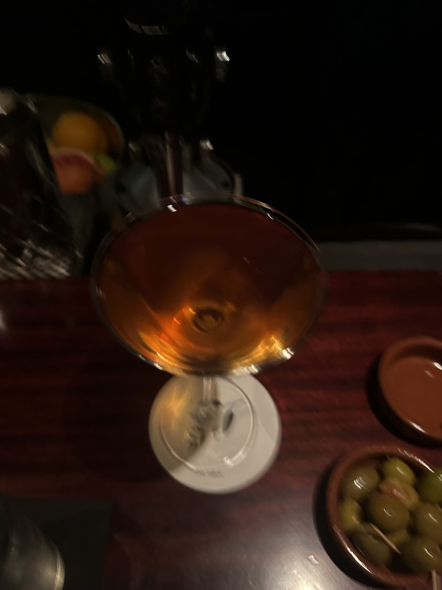 A blurred amber cocktail and olives on a dark bar in Barcelona