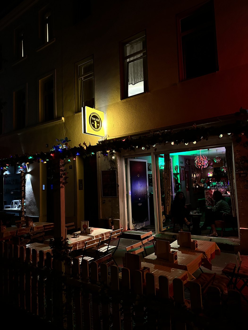 TheBär at night: the lit sign, string lights and guests at the outdoor tables in Cologne