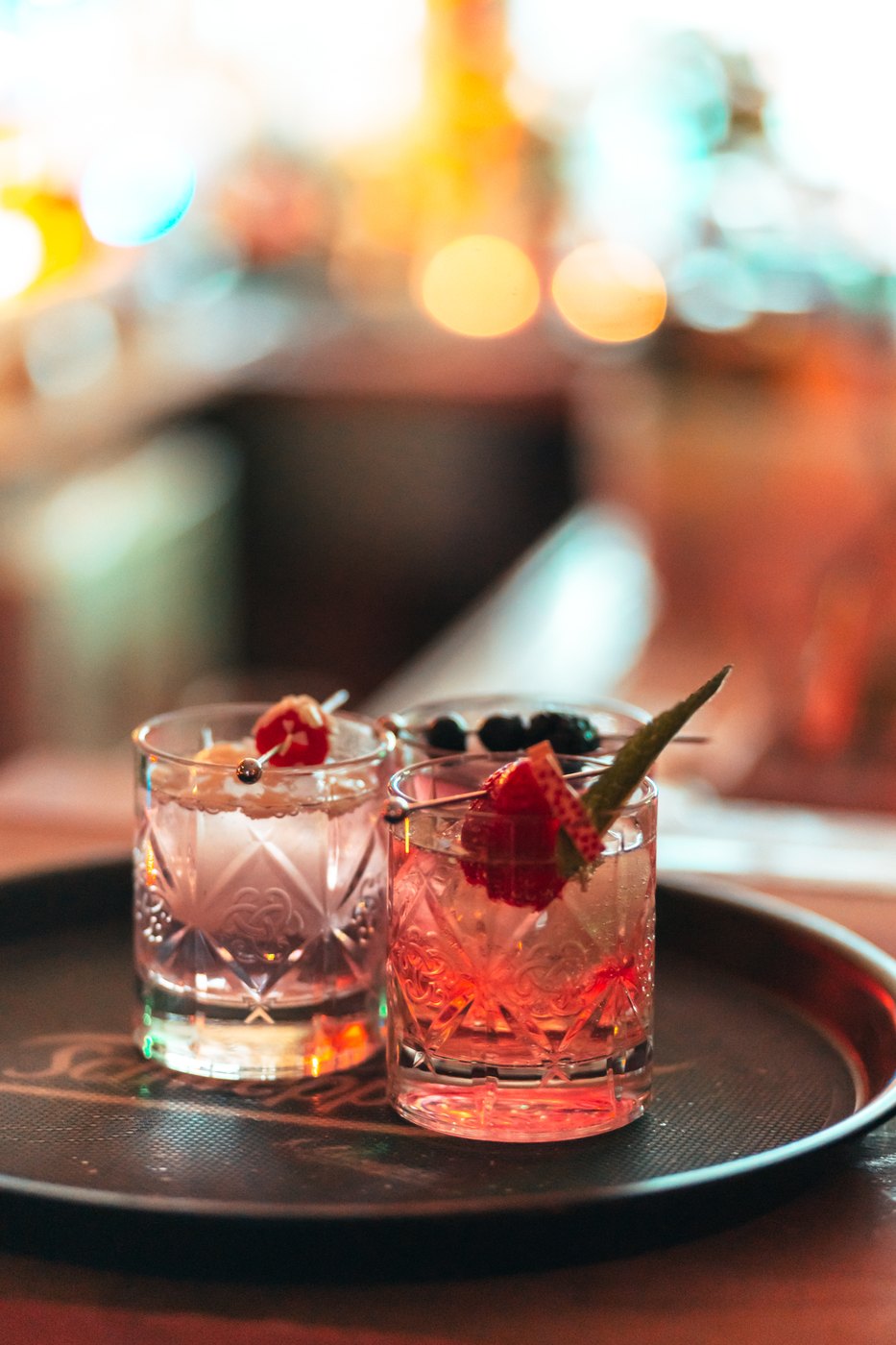 Two gin cocktails with berries on a bar tray at TheBär